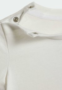 Biały kołnierz koszuli bawełnianej z trzema srebrnymi zatrzaskami, charakteryzujący się miękką fakturą i prostym wzorem. Na krawędzi widoczny jest szew.