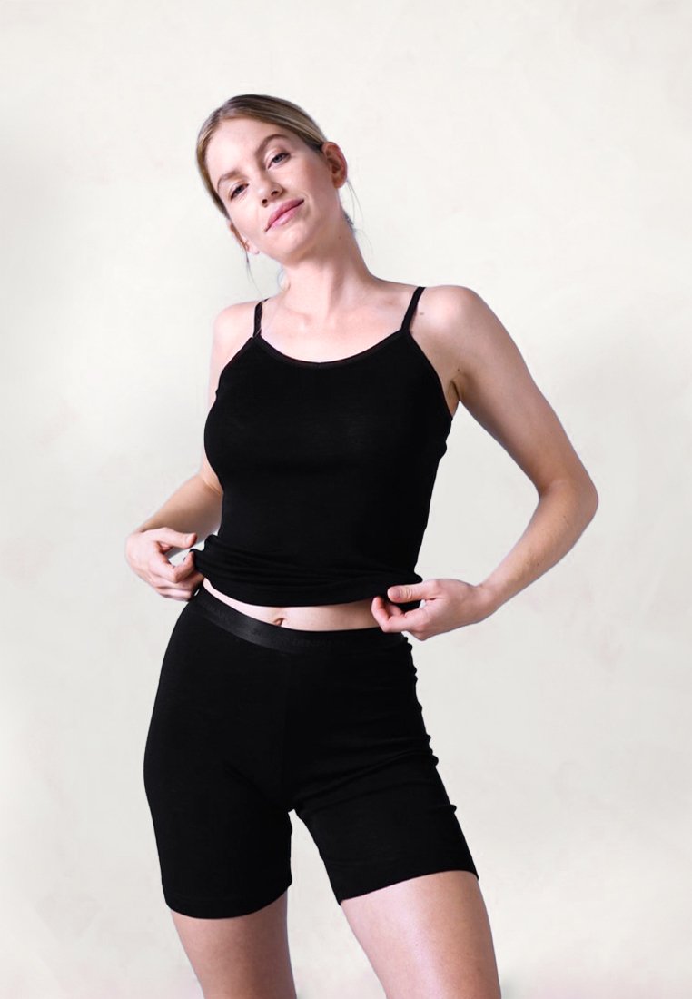 Sort bomulds tanktop med tynde stropper, parret med matchende sorte cykelshorts. Begge dele har en glat tekstur og et enkelt design.