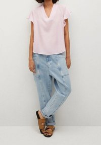 Lyserød kortærmet bluse med V-udskæring, parret med løse lyseblå jeans og brune slip-on sandaler.