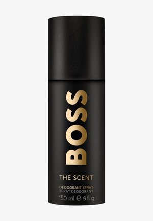 Spray déodorant noir cylindrique avec texte doré « BOSS », étiqueté « The Scent », 150 ml, 96 g, sur fond blanc uni.