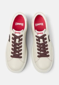 Sneakers bianchi in pelle con lacci marroni, solette rosse e un logo sulla linguetta. Forma curvata e superficie liscia. Suole in gomma.
