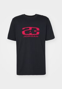 Juodas medvilninis marškinėlis su ryškiu raudonu grafiku, kuriame yra „23“ ir „JORDAN“, trumpomis rankovėmis ir klasikiniu apvaliu iškirpimu.
