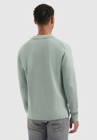 Mintgrünes Langarmshirt mit Rundhalsausschnitt, gerippten Bündchen und glatter Textur. Verfügt über ein dezentes Logo auf der Rückseite.