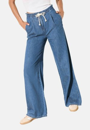 Vida jeans i ljusblått med dragsko i midjan, sidfickor och en slät yta. Försedda med minimala sömnadsdetaljer.