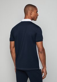 Polo shirt della marina con maniche corte, colletto bianco e pannelli laterali, caratterizzato da un orlo dritto e dettagli di cucitura visibili. Materiale in cotone liscio.
