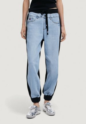 Pantaloni jogger azzurri chiari con pannelli laterali neri, vita elastica e coulisse. Presentano tasche frontali e polsini a costine.