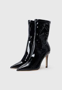 Stivali alla caviglia in pelle verniciata nera con punta affilata, tacco a stiletto alto e un design senza cuciture caratterizzato da una leggera finitura texturizzata.