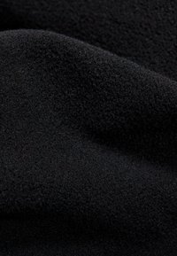 Black fabric with a soft, velvety texture, showing a slight sheen and smooth surface, gathered in folds to emphasize the material's drape.