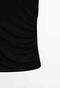 Černý top s nařaseným designem. Vyroben z měkké tkaniny, obsahuje drapovaný detail a přiléhavou siluetu pro štíhlý vzhled.