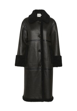 Cappotto in pelle nera con collare e polsini in shearling, dotato di due tasche frontali e chiusura a bottoni visibile, che offre una finitura testurizzata.