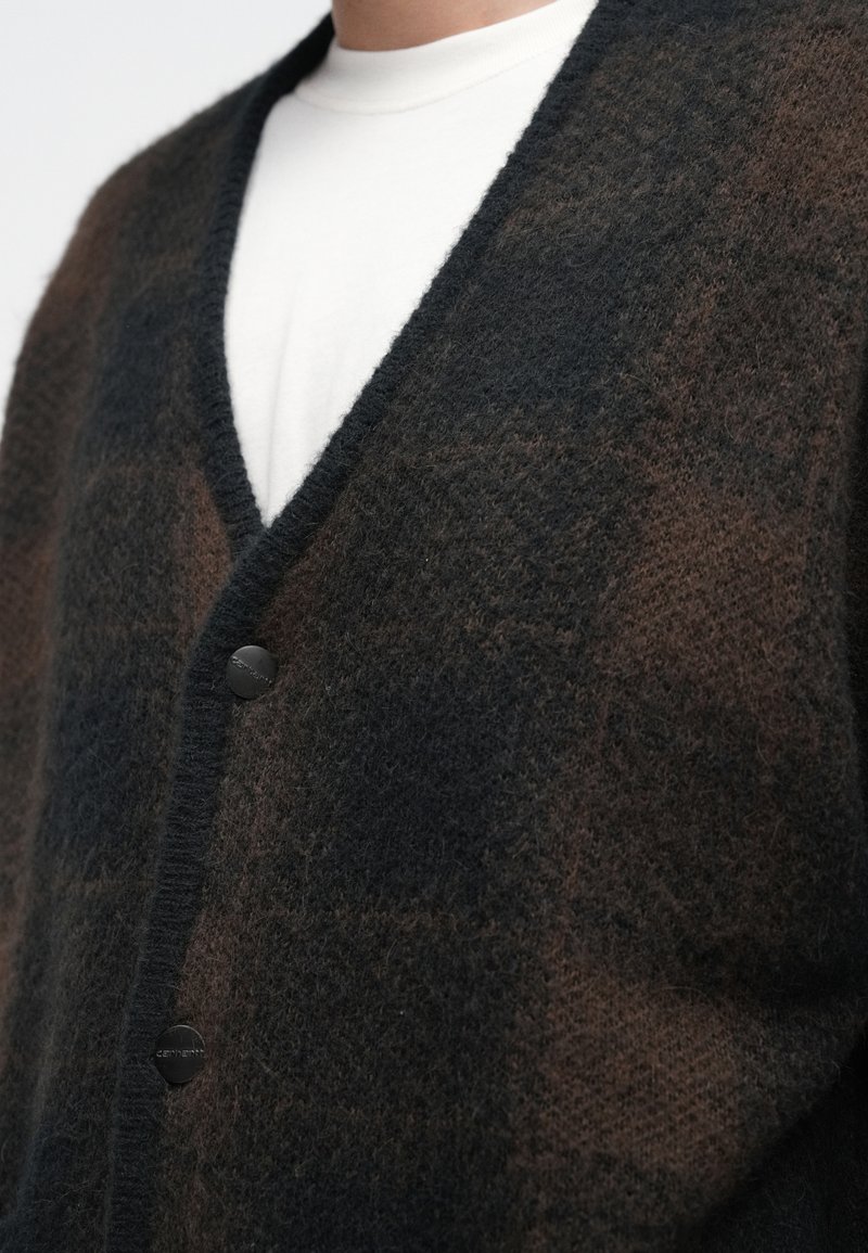 Black and brown checked cardigan made of soft material, featuring a deep v-neck, long sleeves, and black buttons along the front.