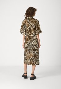 Obleka midi z leopardjim vzorcem, kratkimi rokavi, ovratnikom in ravnim krojem. Narejena iz gladkega materiala, ki vsebuje različne odtenke rjave in bež.