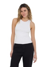 Top bianco senza maniche con una texture liscia, caratterizzato da piccoli punti in rilievo su tutta la superficie. Abbinato a pantaloni neri, il modello si trova in posizione frontale.