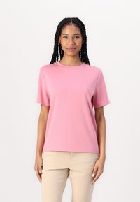 Rosa kortärmad t-shirt i mjuk bomull med en klassisk rund halsringning och en avslappnad passform, kombinerad med ljusbeige byxor.