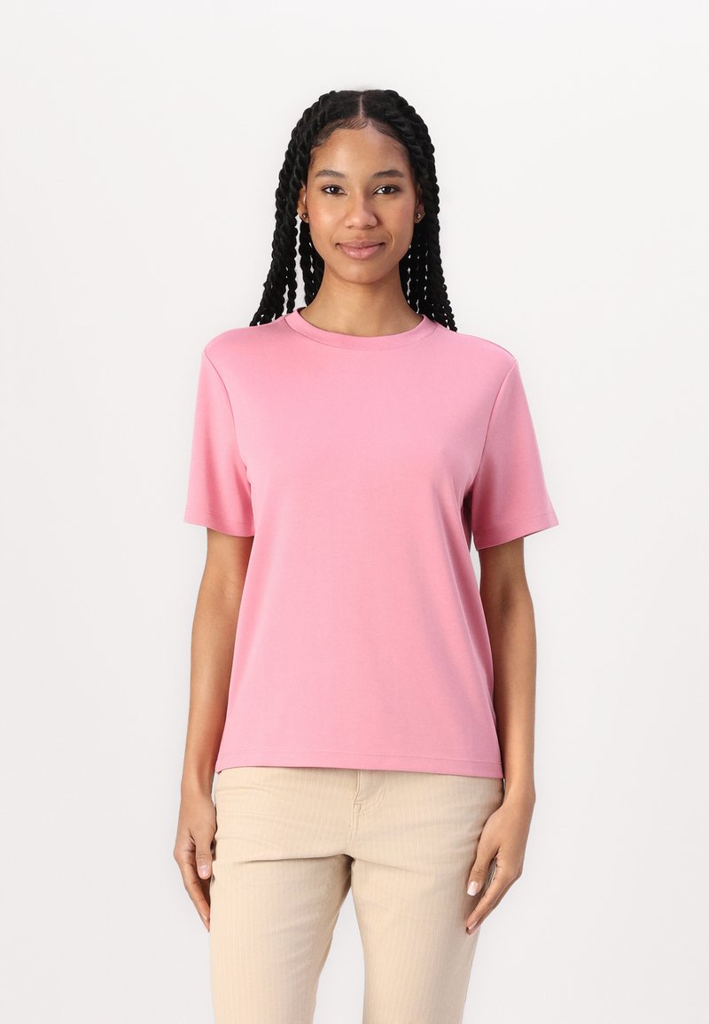 Rosa kortärmad t-shirt i mjuk bomull med en klassisk rund halsringning och en avslappnad passform, kombinerad med ljusbeige byxor.