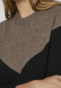 Pullover in maglia con design a blocchi di colore marrone e nero. Texture morbida con scollatura a girocollo e motivo a zig-zag sulla parte anteriore.