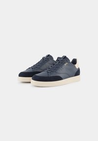 Niebieskie skórzane i zamszowe sneakersy z beżową gumową podeszwą, z sznurówkami i małymi perforacjami na cholewce.