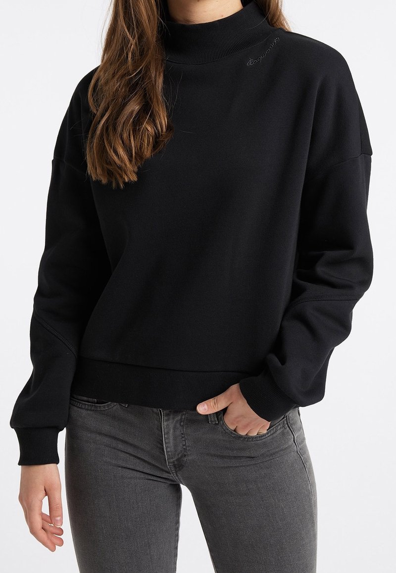 Musta korkeakauluksinen collegepaita, jossa rento istuvuus, resorit hihoissa ja helmassa. Pehmeä kangas, jossa rinnassa hillitty brändäys. Yhdistetty harmaiden farkkujen kanssa.