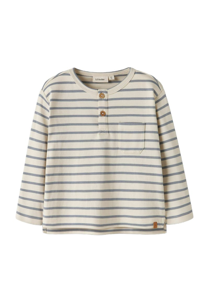 Pasiasta koszula z długim rękawem w kolorze kremowym z jasnoniebieskimi i granatowymi paskami. Posiada okrągły dekolt, pliskę z trzema guzikami oraz kieszeń na piersi.