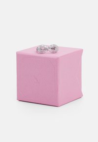 Rosa strukturierte Geschenkschachtel mit einem silbernen Unendlichkeitsring, der mit funkelnden Akzenten verziert ist, oben drauf. Die Box verfügt über ein dezentes, auf der Seite eingeprägtes Logo.