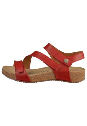 Sandale en cuir rouge avec deux sangles réglables, semelle en liège et semelle intérieure texturée. Elle présente un petit logo métallique sur le côté.