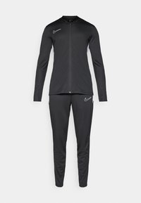 Schwarzer Sporttracksuit mit langen Ärmeln und Reißverschlussjacke. Verfügt über das weiße Nike-Logo und Akzente an den Schultern sowie an den Seiten der Hose.
