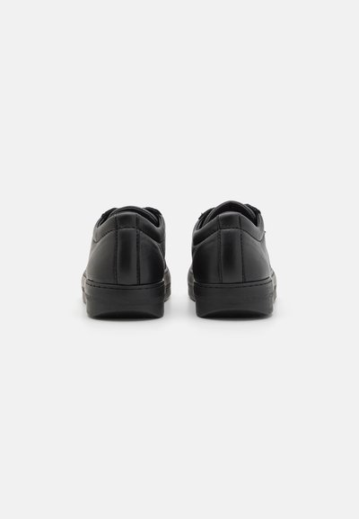 Sneakers din piele neagră, cu vârful rotunjit, guler căptușit și talpă de cauciuc plată. Prezintă detalii de cusătură pe partea superioară și călcâi.