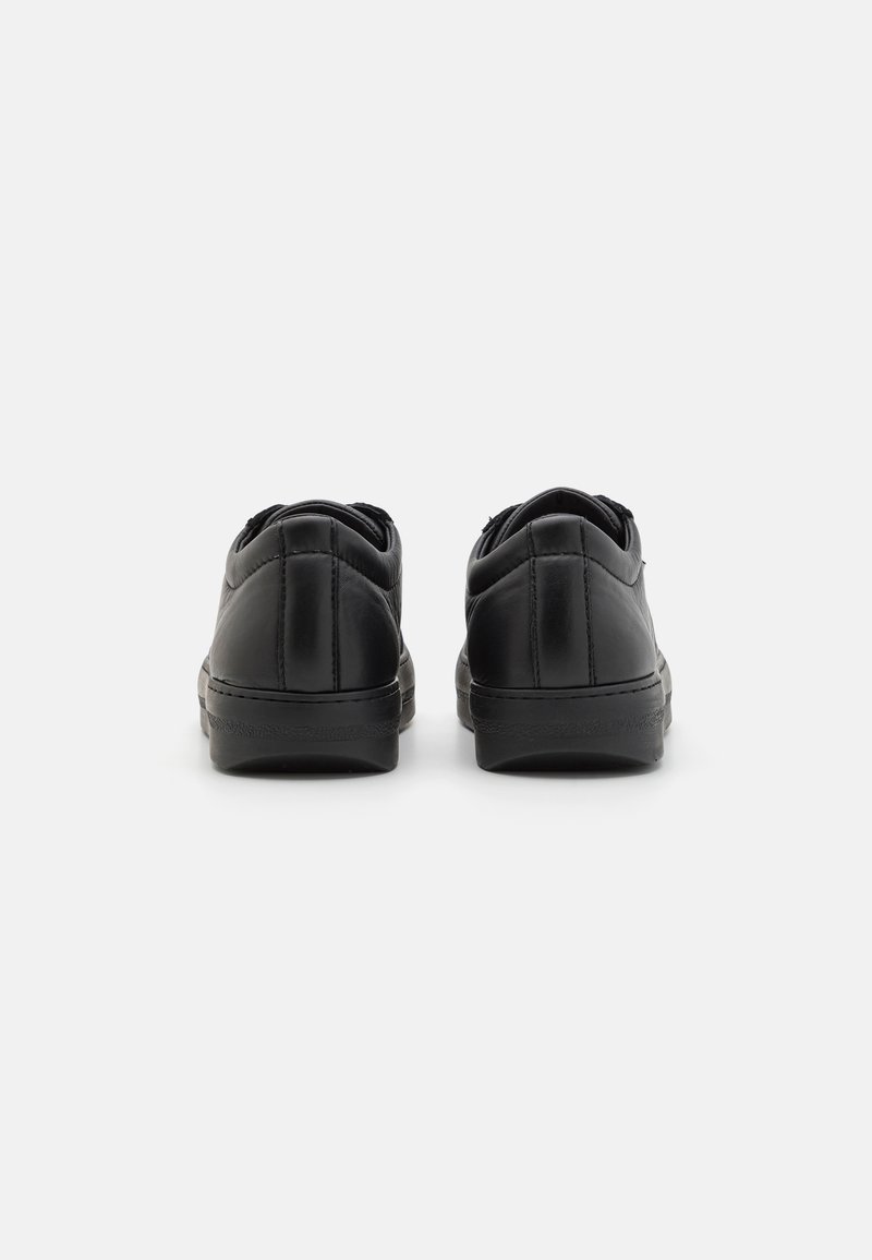 Black leather sneakers with rounded toe, padded collar, and flat rubber sole. Features stitching details along the upper and heel.