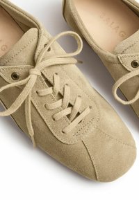 Scarpe in suede beige con punta arrotondata, design con lacci e dettagli di cucitura discreti. Texture liscia con occhielli metallici per i lacci.