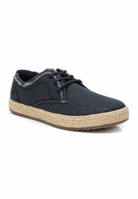 Zapatillas de lona azul oscuro con un acabado texturizado y bordes deshilachados. La plantilla de cuerda de yute y la suela de goma ofrecen contraste y durabilidad.