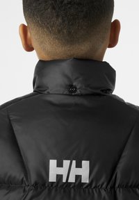 Crna puffer jakna s visokim ovratnikom, koja sadrži detalje s gumbima i reflektirajući "HH" logo na leđima. Glatka, sjajna tekstura.