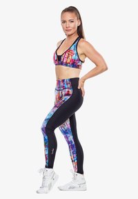 Sportbeha en high-waisted leggings in een heldere meerkleurige print met zwarte accenten, gemaakt van rekbare, prestatiegerichte stof.