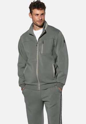 Graue Jacke mit Reißverschluss und hohem Kragen, Fronttaschen und einer Brusttasche. Verfügt über kontrastierende Einfassungen entlang des Reißverschlusses und der Nähte. Weiche Textur.