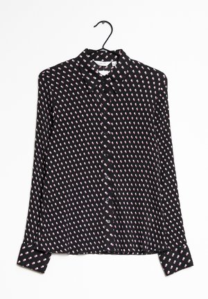 Blouse noire à manches longues boutonnée avec un petit motif abstrait de points roses et blancs, suspendue sur un cintre noir sur fond blanc.