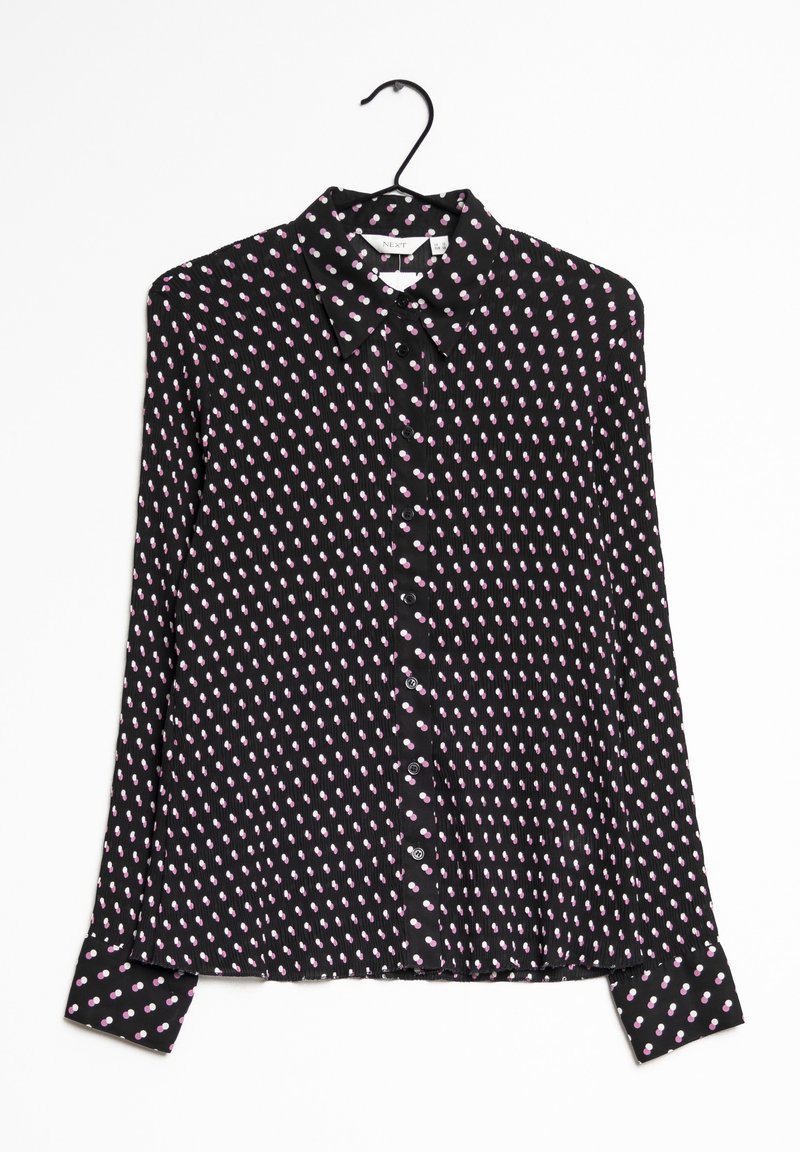 Blouse noire à manches longues boutonnée avec un petit motif abstrait de points roses et blancs, suspendue sur un cintre noir sur fond blanc.