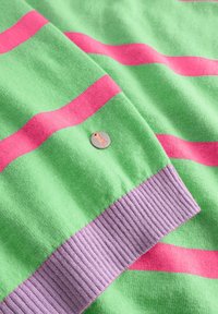 Groen stof met horizontale roze strepen, paarse geribbelde manchet en een kleine ronde zilveren hanger met een oranje giraffe silhouet.