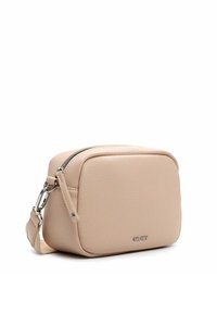 Pequeño bolso bandolera de cuero beige con cremallera plateada, correa ajustable y logo metálico de la marca en el panel frontal.