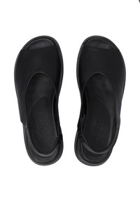 Schwarze Leder-Sandalen mit offener Zehenpartie, geschwungener Obergestaltung und minimalen Riemen. Texturiertes Fußbett mit sichtbarem Branding auf der Sohle.