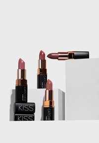 Quattro rossetti con un design nero opaco e oro rosa, che mostrano diverse tonalità di rosa. Un rossetto è parzialmente esteso.