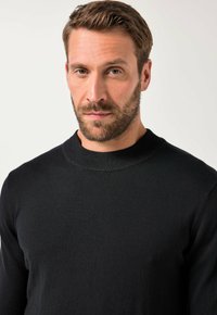 Schwarzer Strickpullover mit Rundhalsausschnitt und langen Ärmeln. Glatte Textur, taillierte Form, keine sichtbaren Muster oder Akzente.