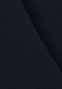 Marineblauer Strickstoff mit glatter Textur, der eine diagonale Naht aufweist und ein geschichtetes Aussehen erzeugt. Keine Muster oder auffällige Hardware sichtbar.