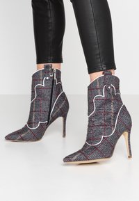 Gray plaid ankle boots with pointed toes and high heels. Features a textured fabric with white stitching accents and a side zipper.