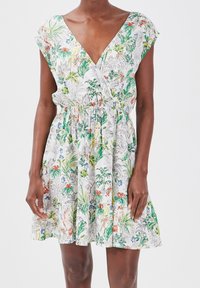 Sukienka w kwiatowy wzór, z dekoltem w serek, krótkimi rękawami, elastyczną talią i rozkloszowanym dołem. Kolory to zielony, czerwony i pomarańczowy na białym tle.