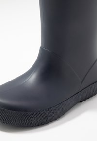 Botte de pluie en caoutchouc bleu marine avec une surface lisse, une semelle texturée et une forme profilée. Présente un bout arrondi et un design sans couture.