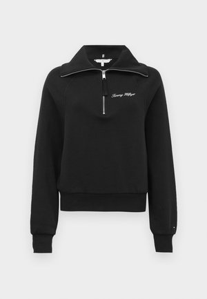 Sudadera negra con cuello alto, cierre de medio zip en la parte delantera y puños acanalados. Presenta texto bordado y un diseño de corte relajado.
