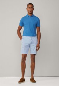 Polo en coton bleu associé à un short bleu clair. Le polo comporte un logo minimaliste, tandis que le short a des poches latérales et une coupe droite.