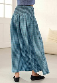 Gonna lunga a quadri blu e neri con vita arricciata, tessuto morbido e vestibilità rilassata. Abbinata a scarpe nere ballerina.