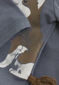 Katoenen T-shirt in gedempt blauw met een bruin en witte grafisch patroon. Kenmerkt zich door textuurstof, een zachte afwerking en een decoratief kwastje.