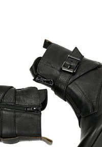 Czarne skórzane botki za kostkę z fakturowanym materiałem, regulowanymi klamrami, zamkami błyskawicznymi oraz kontrastującymi akcentami na krawędziach.