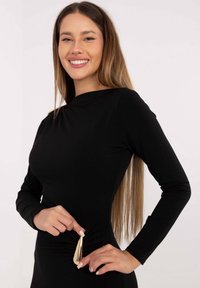 Czarny top z d�ługim rękawem o dopasowanym kroju. Posiada marszczony detal z boku oraz złoty akcent w talii, gładką teksturę i prostą sylwetkę.
